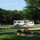 Large RV in a landscaped area with playground nearby — shows open RV sites, landscaping and family-friendly facilities (Rates/Reservations page).