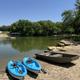Kayaks and a jon boat on the sandy beach of the stocked lake, swim platform beyond