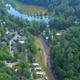 Aerial drone view showing the campground layout, lake, cabins/RV sites and surrounding forest — strong overall property overview (page: Accommodations).