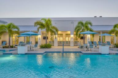 Bonita Terra pool at dusk with clubhouse, outdoor bar seating, and depth markers