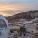 Closer ground-level view of domes with seating/firepit and desert landscaping — useful detail of campsite amenities and guest area (source page: Contact/site imagery).