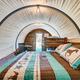 Interior of a covered-wagon glamping unit with bed, bunk and wooden back wall — clearly shows the property’s unique wagon accommodations (image sourced from homepage/gallery).
