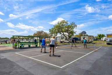 Outdoor courts with people playing (pickleball/tennis) and RVs visible in the distance — shows active recreational area from the campground photo gallery.