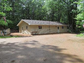 Exterior view of a single-story building on gravel drive surrounded by trees — likely campground facilities (image appears on the site's Pictures page and gives context of on-site buildings).