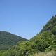 A light blue sky with green mountains.
