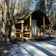 Small log cabin on a wooded site with a porch — clearly depicts the campground’s rental cabins (page context: Catskills Cabin Rentals) and the cabin setting within the park.