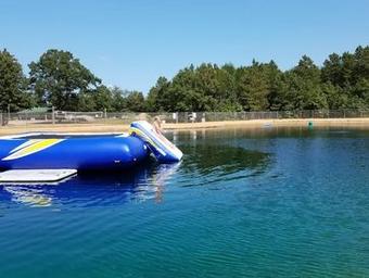 Ground-level image of the pond/pool with an inflatable—shows on-site recreational water amenity and fencing, useful for guest-facing gallery (source: Seasonal Site Information).