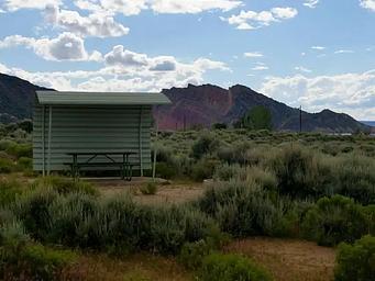 Picnic table with a shelter covering one side and over head.