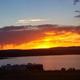 Dramatic sunset with an RV silhouette along the lakefront — clearly depicts an on-site RV and lakeside setting referenced on the RV Park page, useful for showing available RV pitches and scenery (source: /rv-park).