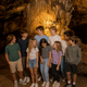 Well-lit interior shot of a large cave formation with a group of children — highlights the cave attraction and guided-tour experience (used on Birthdays page).