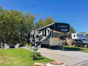Premium RV lot with a parked fifth-wheel, patio area and landscaping — demonstrates typical campsite setup and guest space on the property.