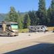 Clear view of two RVs parked on paved/gravel pads with picnic setup and trees in background — shows actual RV pitches on the Lakeview RV Retreat property (file is on the property website page).