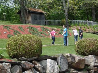 Image of guests playing putt‑putt on a landscaped green with rock wall and grounds signage — highlights onsite recreational facilities (mini-golf) and landscaped grounds on the property gallery.