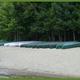 Row of canoes on a sandy beach backed by trees — shows on-site recreational equipment/shoreline access and campsite beach area (appears in Rates/page images).