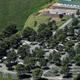 Aerial overview of the entire RV park showing roads, RV pads, trees and surrounding fields — good overall site layout shot (matches property homepage slide 'Aerial').