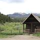  Brown forest service cabin surrounded by green trees and rolling hills