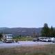 Wide-angle dusk shot showing a row of RVs and cars on the campground pads with surrounding mountains — good overall view of site layout and setting from the property's gallery page.