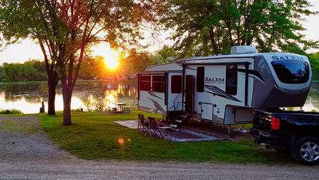 RV parked lakeside at sunset showing an RV site, firepit area and lake — useful overview of RV pitches and waterside setting (matches RVing/gallery content).