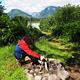A person building a teepee of sticks in a rock firepit with mountains is background
