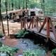 Wooded campsite area with RV/trailer, decorative bridge and landscaping — useful view of campground campsites and site character (appears in site gallery/rates pages).