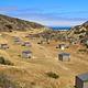 Eight foot tall wind shelters on a dry, grassy terrace overlooking the ocean. 
