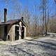 Vault toilet facility sits in gravel parking lot of campground.