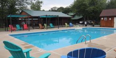 Outdoor swimming pool with colorful chairs and shaded seating areas.