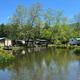 Pond view with flowering marginal plants, campground buildings and RVs along the water — strong scenic/property feature shown on homepage.