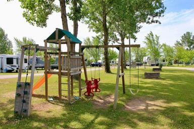 Playground with visible RV sites and trees in the background — useful for showing family amenities and site layout (source page: homepage images).