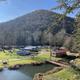 Aerial/overview of the campground showing RVs, sites, a small bridge and pond with hillside in background — good overall layout shot from the homepage.