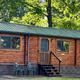 Exterior of a wood cabin on campground grounds with neighboring RVs visible — good clear view of cabin lodging offered. Source: property photo gallery / main site hero image.