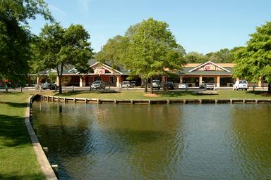 View of Camptown Center and adjacent pond from the site — shows community/facility buildings and on-site water feature useful for property gallery. Source: Home - Ocean Lakes Family Campground.