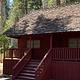 Portion of roof and porch of old, red cabin.