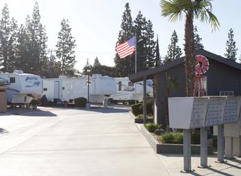Ground-level view of the park drive, mailboxes and flag with RVs in background — helpful for entrance/onsite atmosphere and orientation (homepage/gallery context).