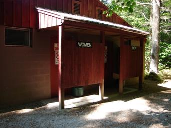 Exterior of restroom/showers building (Men/Women entrances) — shows on-site amenities and facilities available to campers. Source: About Us gallery.