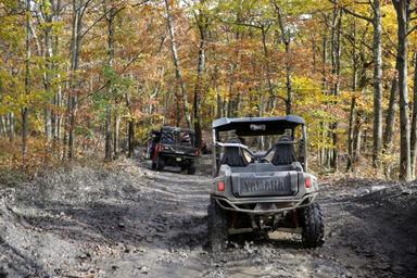 Tree‑lined gravel road through the campground with RVs parked at sites — useful for showing site roads, spacing and wooded character (from ATV/ATV camping page gallery).