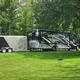 Close view of a large RV parked on a grassy, tree-shaded site with picnic table — useful detail shot of an individual RV pitch and grounds (gallery image).
