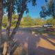 Ground-level panoramic of campsites with trees, RVs and picnic areas — clear view of campsite layout and vegetation; used as a background on the 'Campsite Rates & Reservations' page.