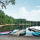 Lakeshore view with small docks and kayaks/canoes on a sandy beach area — good scenic shot showing lakefront access and watercraft available to guests (homepage image).