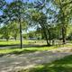 Open campground area with multiple gravel RV/campsite pads, picnic tables and mature trees — good overall view of site layout and grounds (used as site social image on the property page).