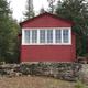 Back view of historic Post Creek Guard Station, red cabin, with white trim around windows.