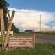 Entrance/property sign at the roadside identifying Wild Yough Glamping Huts with surrounding landscape — useful exterior/arrival photo (page: “How we work - Wild Yough Glamping Huts”).