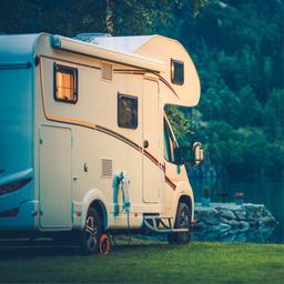 RV parked at a waterfront campsite showing vehicle hookup area and lake backdrop; matches the ‘RV sites’ context on the website describing RV accommodations.
