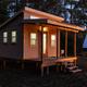 Twilight exterior of a tiny cabin with lit porch; good complementary view of lodging ambience and on‑site accommodations from the property gallery.