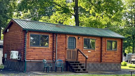 Exterior of a wood cabin on campground grounds with neighboring RVs visible — good clear view of cabin lodging offered. Source: property photo gallery / main site hero image.