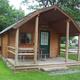 Front view of a rustic cabin on a grassy site with nearby RVs visible — useful to show cabin lodging option on the campground (file from the campground 'waystostay' photos).