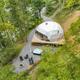Aerial drone view of a private geodesic dome on its deck with hot tub, firepit and access road — good overall site overview matching the property’s dome retreats shown on the home page.