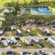High-angle shot of RV loops and cabins beside a pond — clear depiction of RV parking, sites and on-site lodging visible on property grounds.