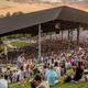 Wide daytime photo of the Bethel Woods pavilion and surrounding lawn seating with crowds — shows the main event venue and adjacent grounds, useful for conveying the site’s facilities (from the site homepage).