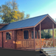 Exterior photo of a family cabin with porch and rocking chairs — good depiction of on-site cabin lodging shown elsewhere on the property pages.